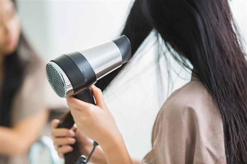 a woman using blow dryer on fine hair