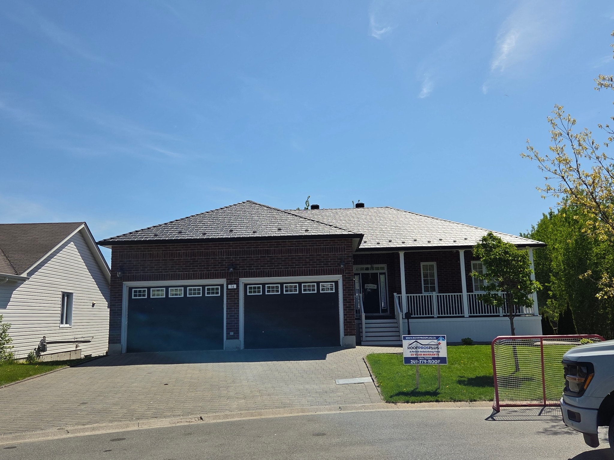 Residential home with a newly installed metal roof, highlighting high-quality roofing materials and professional metal roof installation. A contractor sign in the yard suggests recent roofing work by Roof Pros Plus, ideal for homeowners researching metal roof cost and installation options.