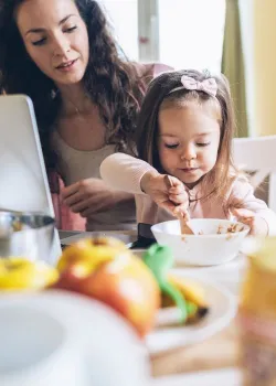 image of child eating cereal while mom works