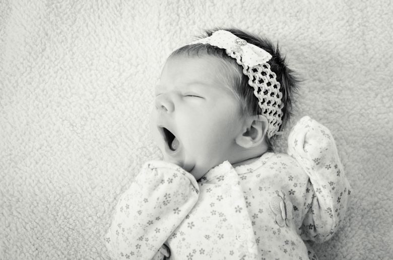 beautiful baby girl in bow yawning