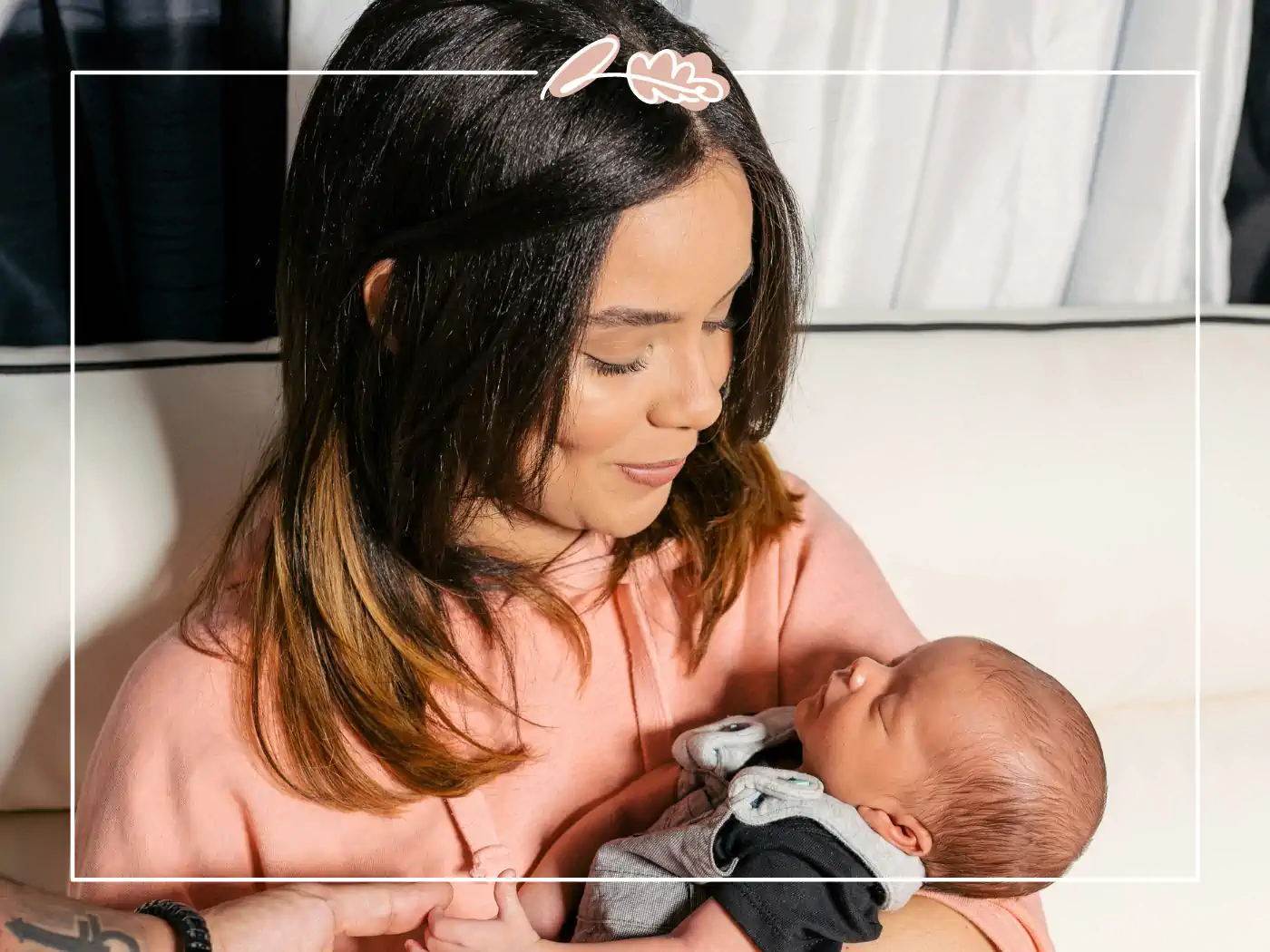 A women in a pink top holding a newborn baby and smiling. Fabulous Flowers and Gifts.