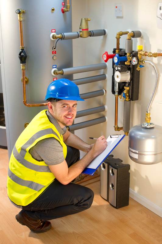 Installateur mit Sicherheitsausrüstung prüft Heizungsanlage.