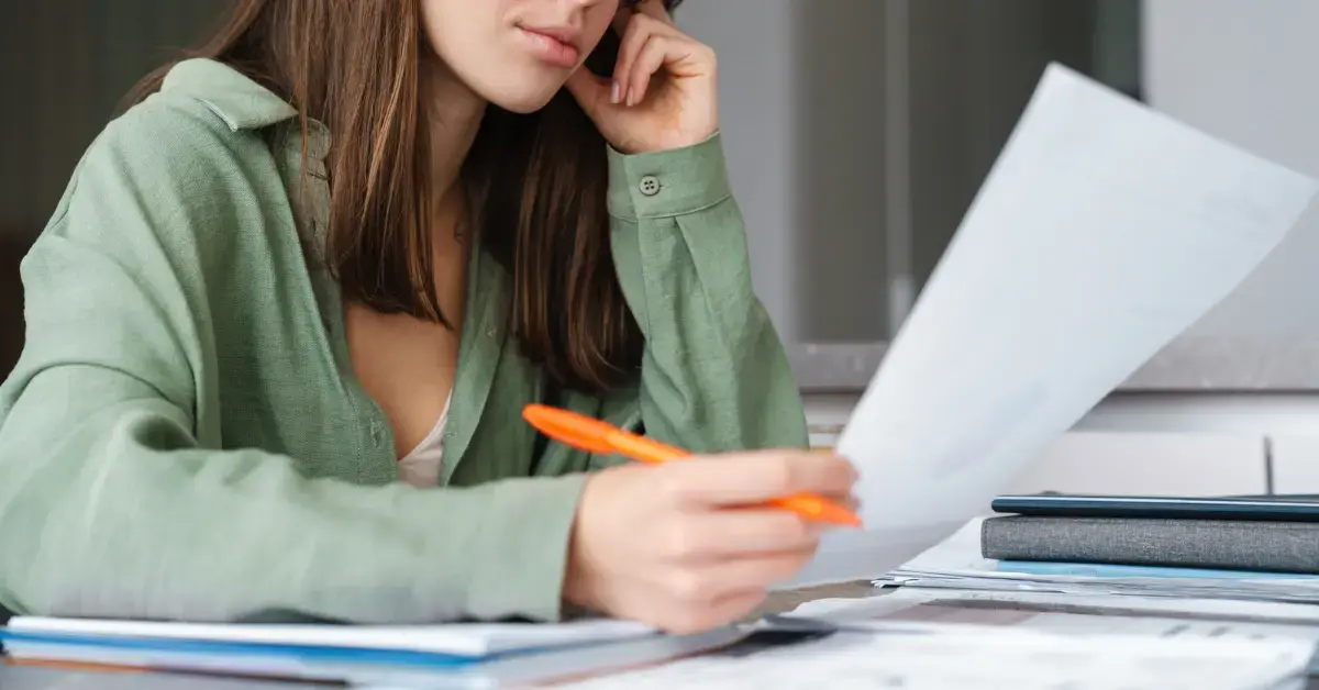 Woman comparing the best business structure for OnlyFans, reviewing LLC and S corp options at her desk.