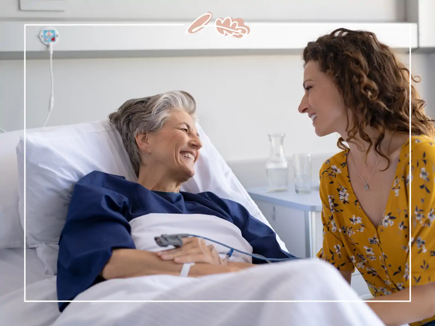 Elderly woman smiling in a hospital bed, visited by a woman in a yellow floral dress, Fabulous Flowers and Gifts