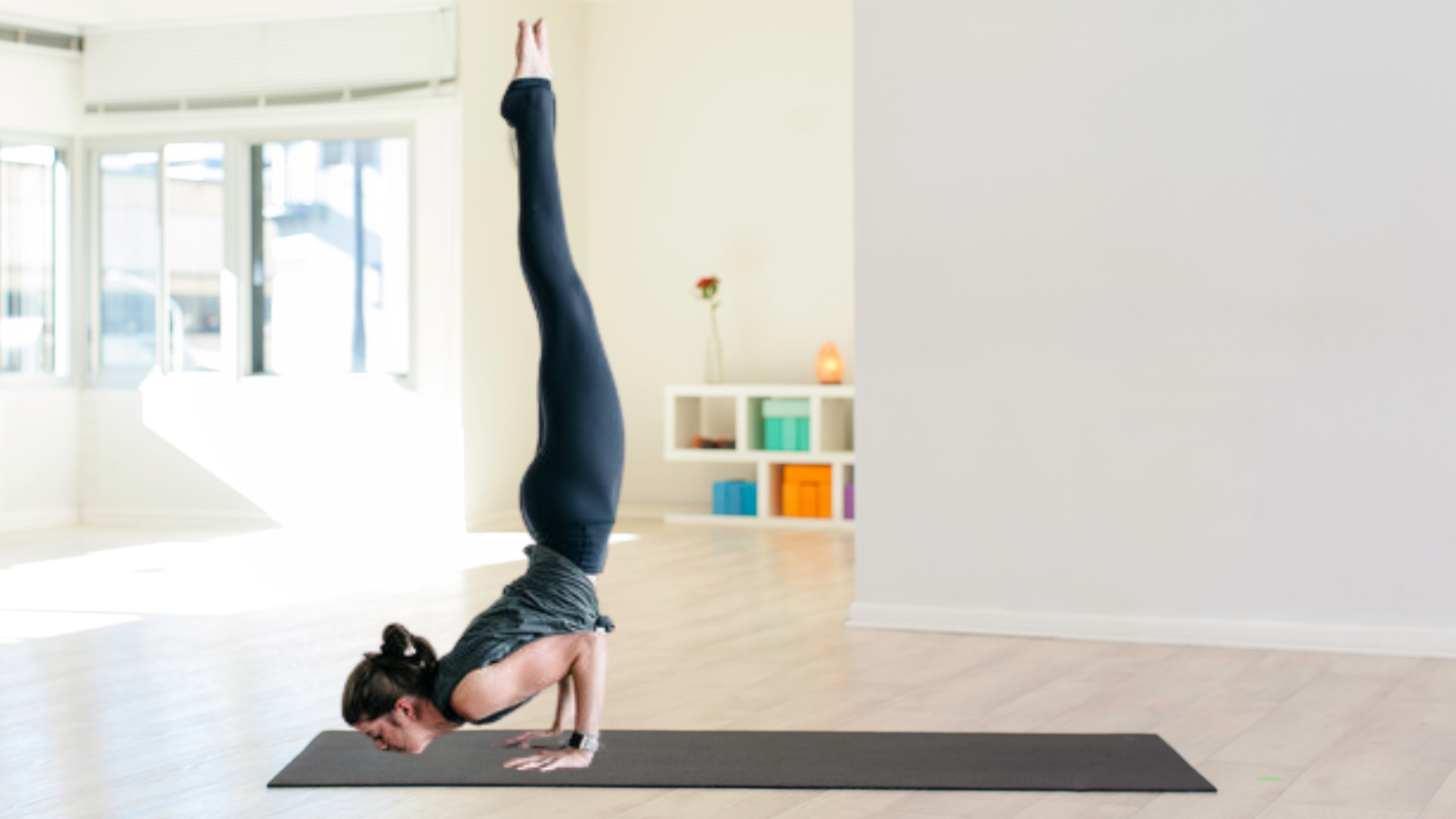 woman doing the chin stand in a white yoga studio