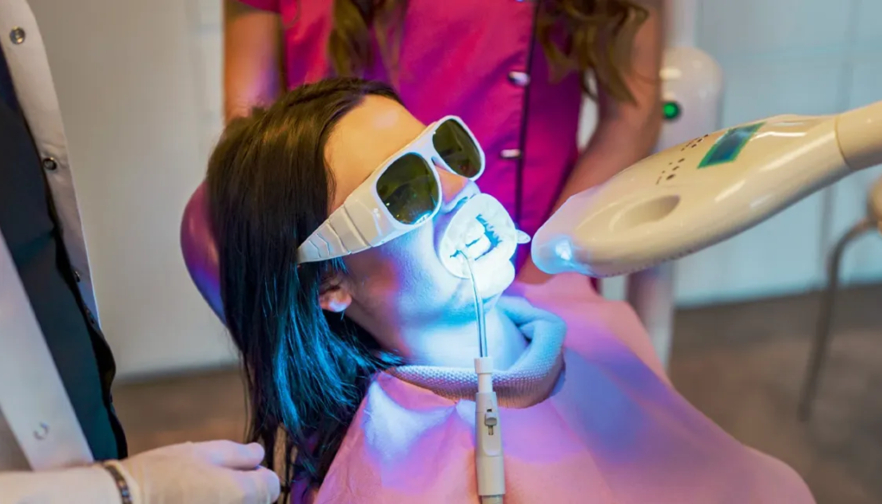 Tannbleking: Få hvitere tenner på en trygg måte 17 "Kvinne får profesjonell tannbleking med blått lys hos tannlege."