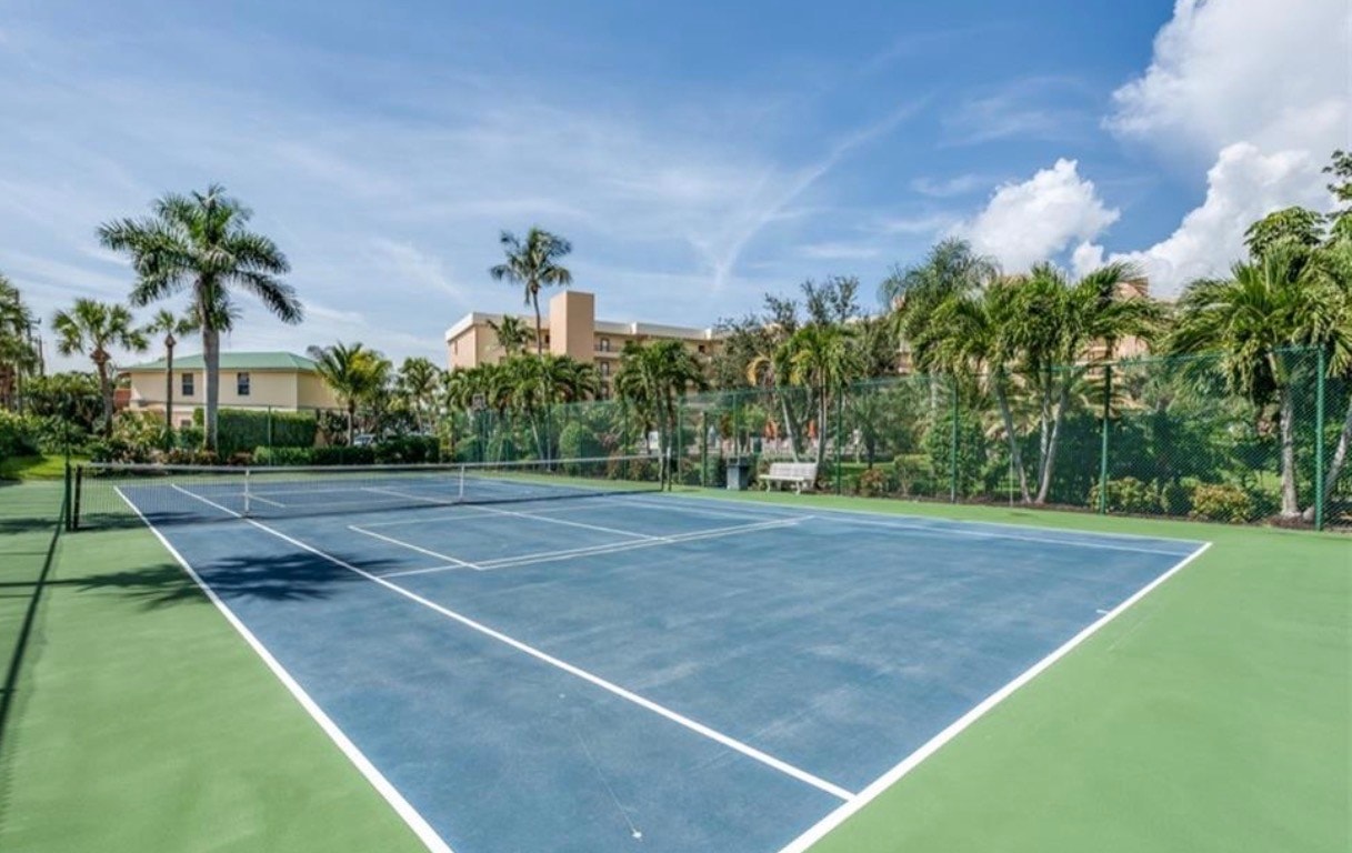The image depicts a resort-style swimming pool at Punta Rassa, surrounded by lush palm trees and offering stunning waterfront views of San Carlos Bay. This tranquil setting is ideal for relaxation and enjoying the beautiful Southwest Florida weather.