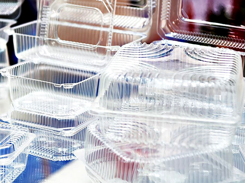 Clear plastic food containers stacked on a surface, some open and some closed, made of Biodegradable plastic.