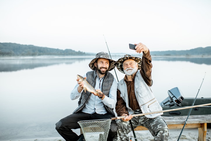 Grandfather and son fishing on a lake. 