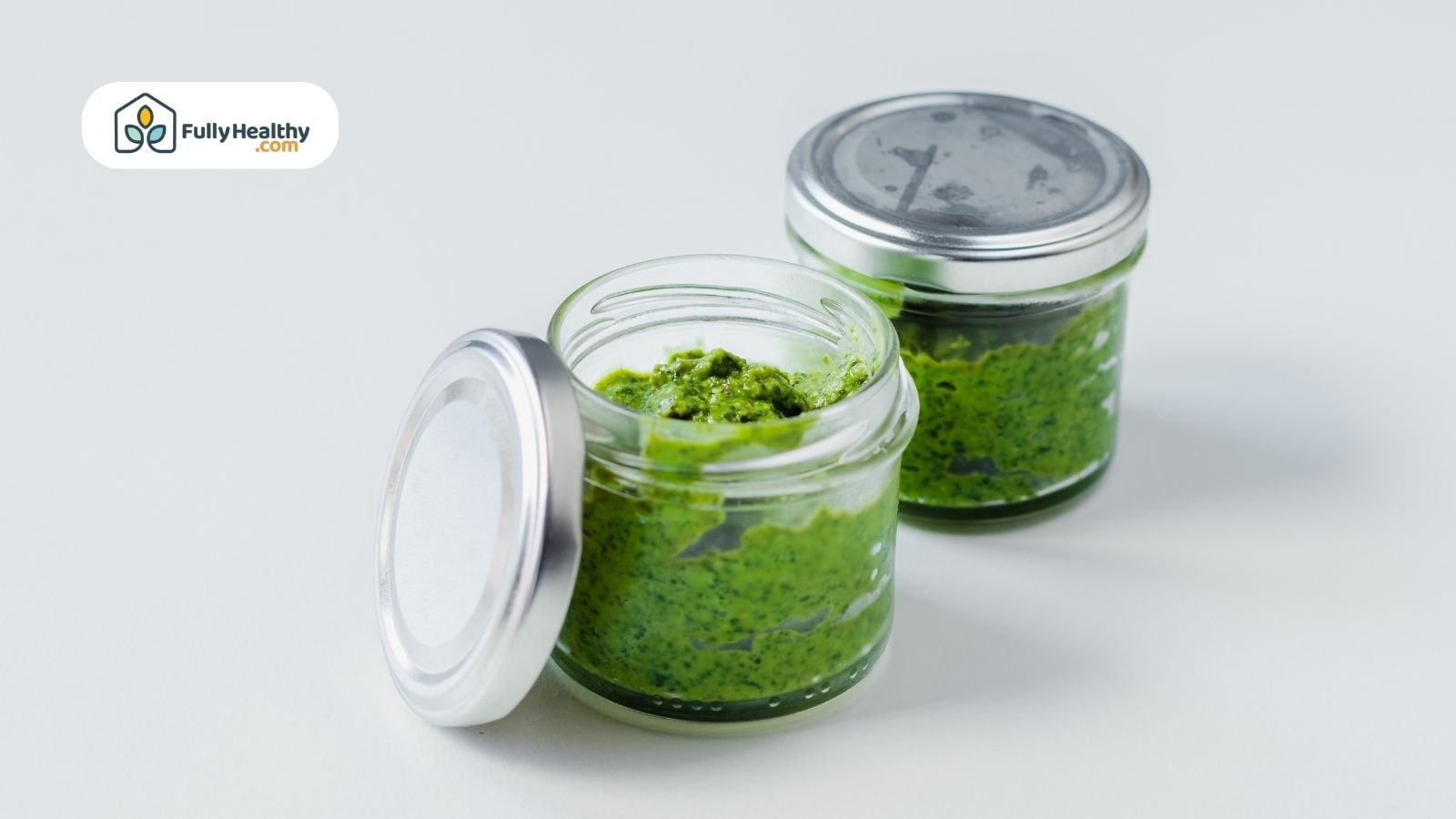 Two small jars of homemade basil pesto with silver lids removed