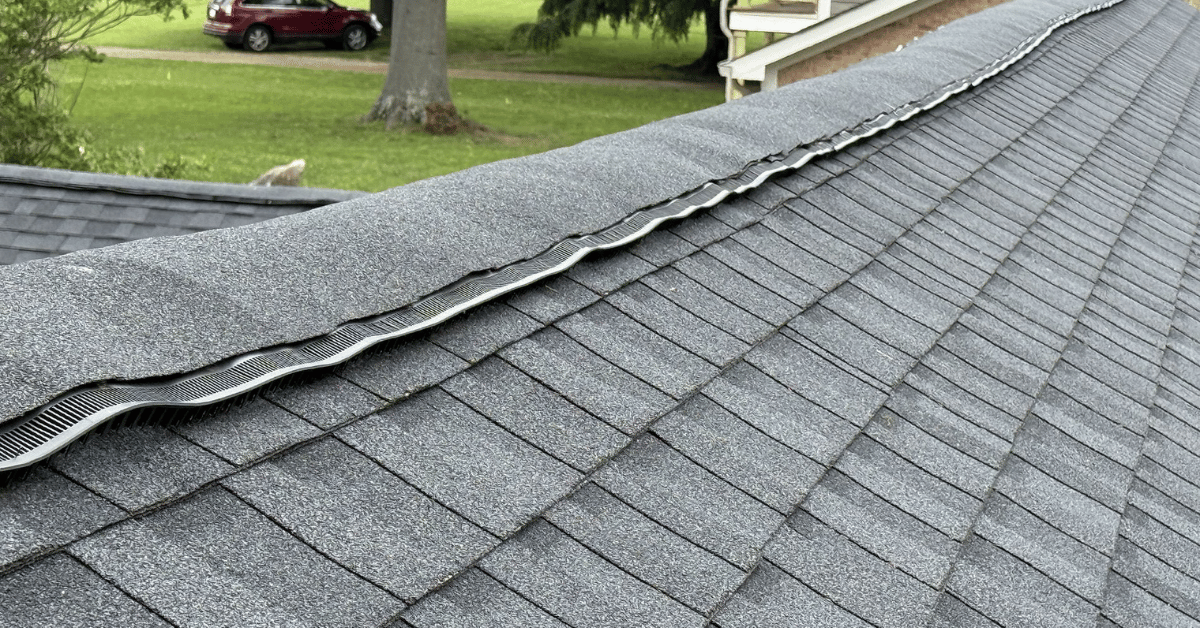 Ridge vent system on asphalt shingle roof showing visible distortion from prolonged exposure to high heat in Tennessee.