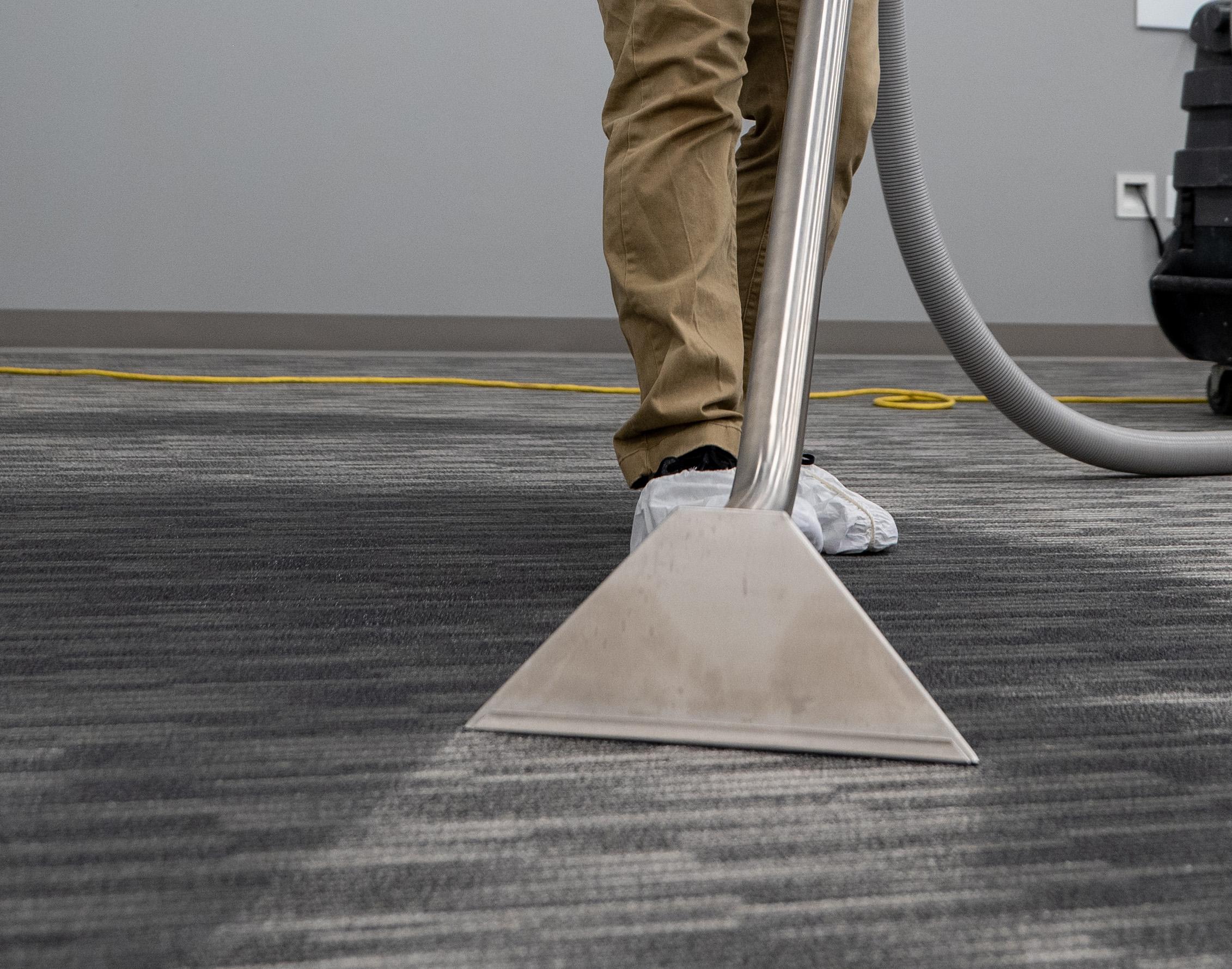 A restoration technician is using specialized water extraction equipment on a wet floor, actively engaging in the water damage restoration process to remove excess water and prevent mold growth. This scene highlights the importance of quick response and effective water removal techniques in mitigating further damage during a water emergency.