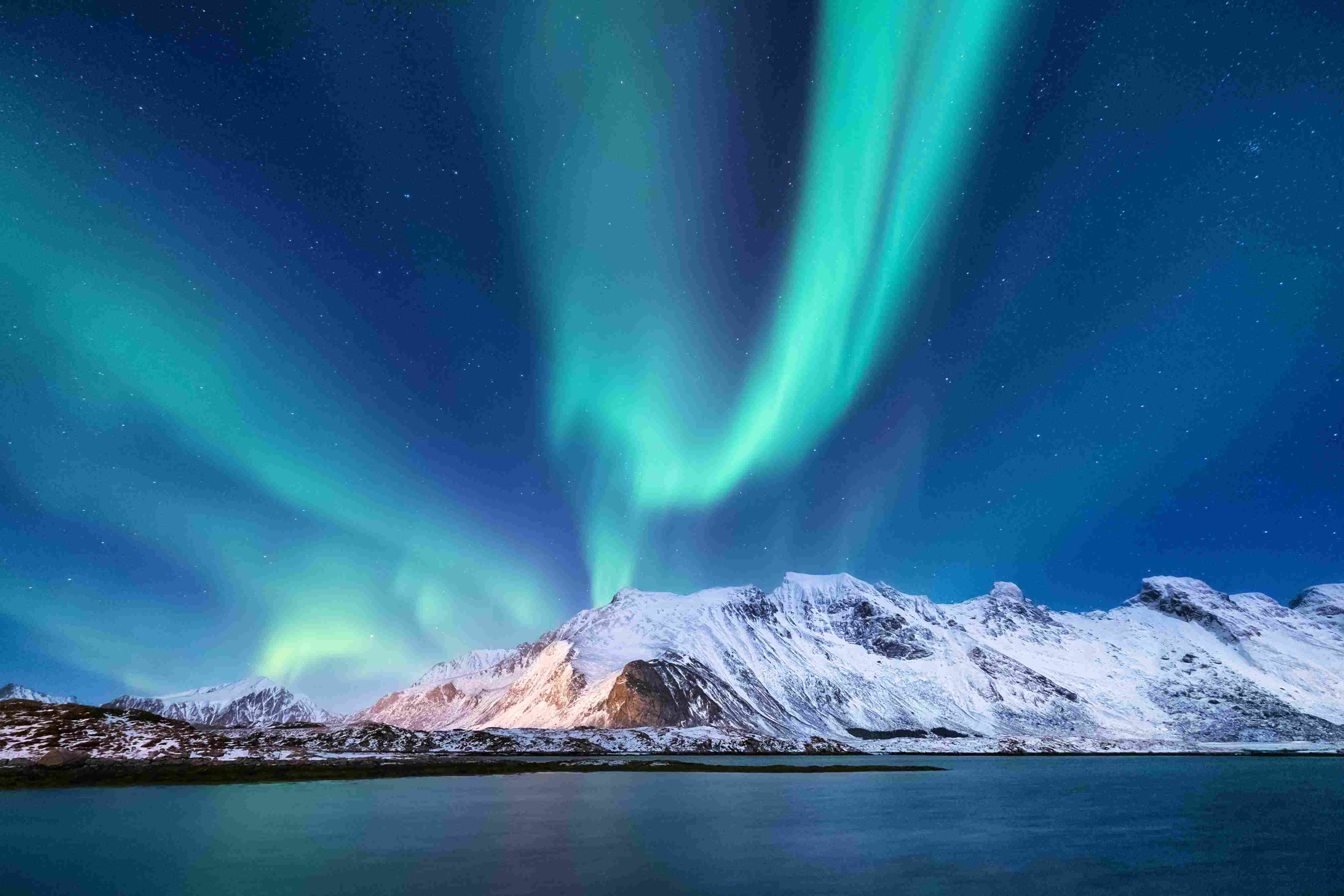 Nocny zimowy krajobraz z zieloną zorzą polarną nad górami i odbiciem na powierzchni wody