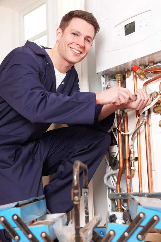 Lächelnder Installateur arbeitet an Kupferrohrleitungen eines Heizungssystems.
