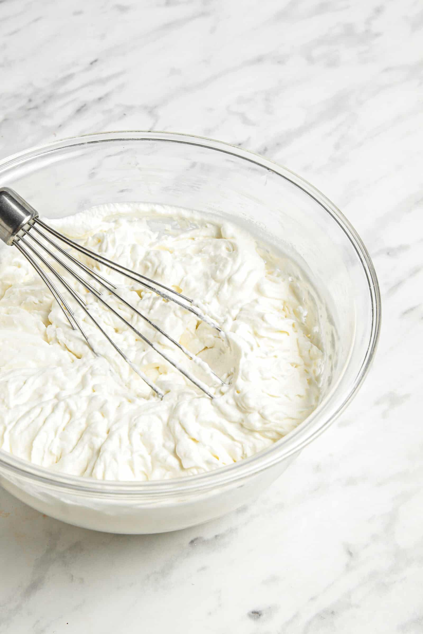 bowl of whipped cream with a whisk in it