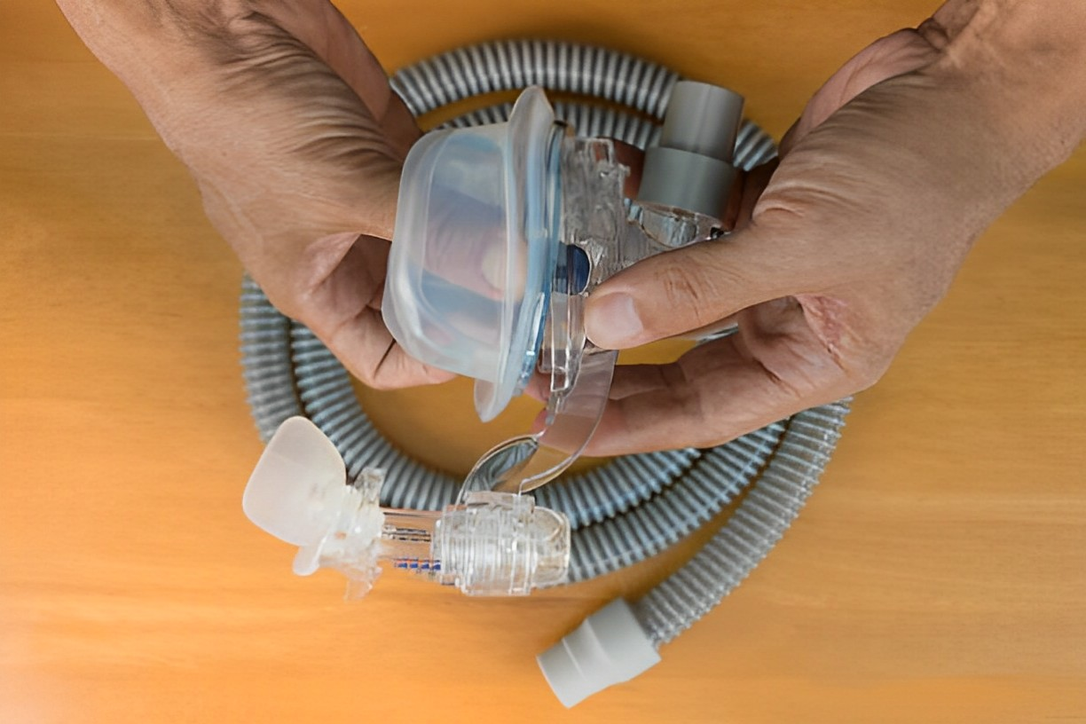 A photo of a hand of a man disassembling a CPAP mask