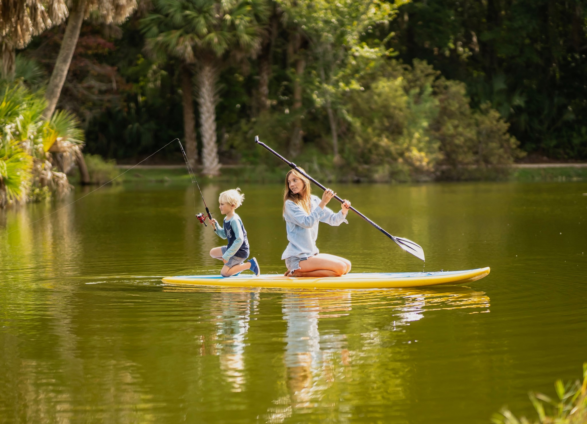 child fishing on a paddle board