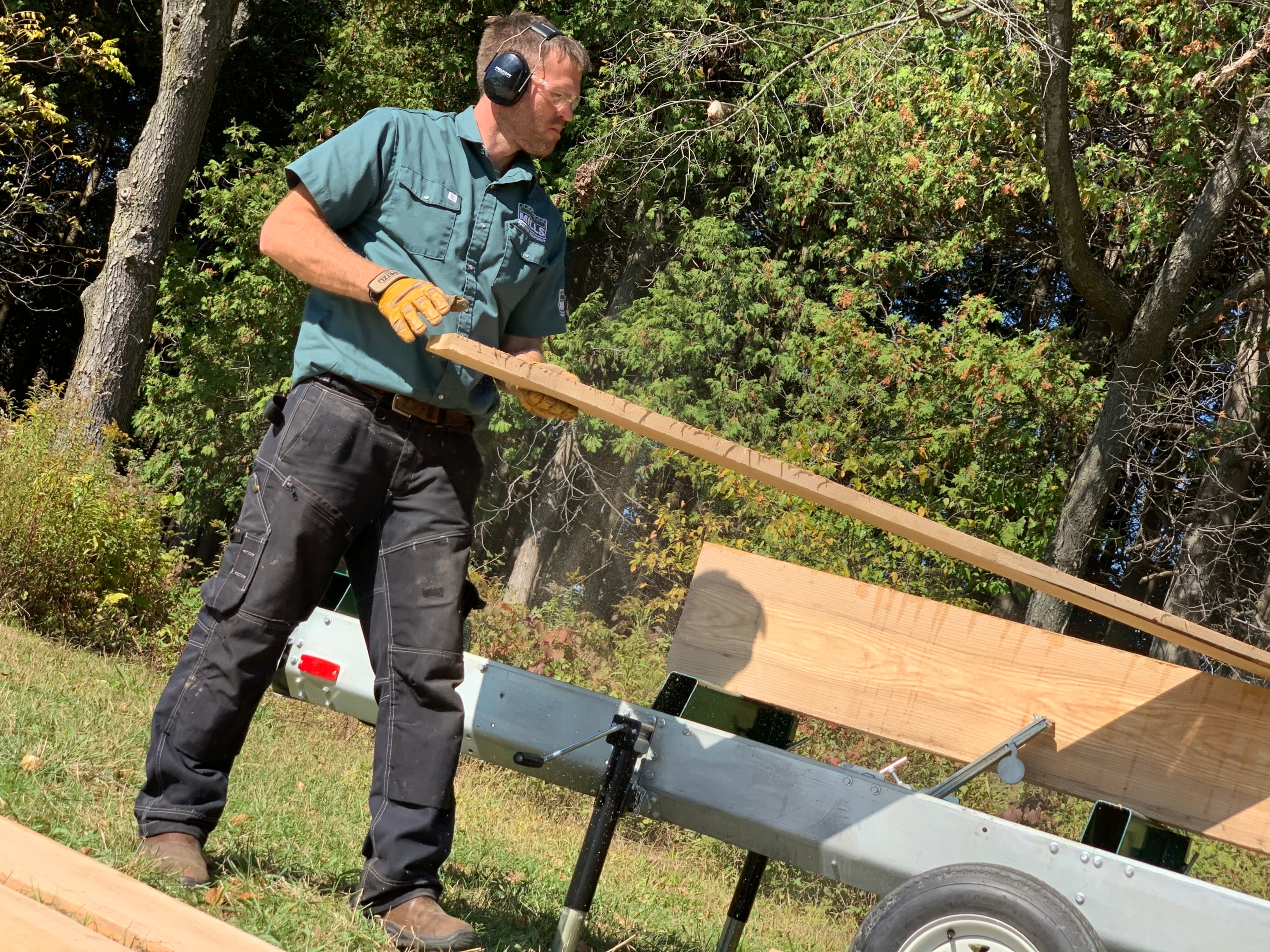 A portable sawmill operator pulling a board off of a sawed cant.