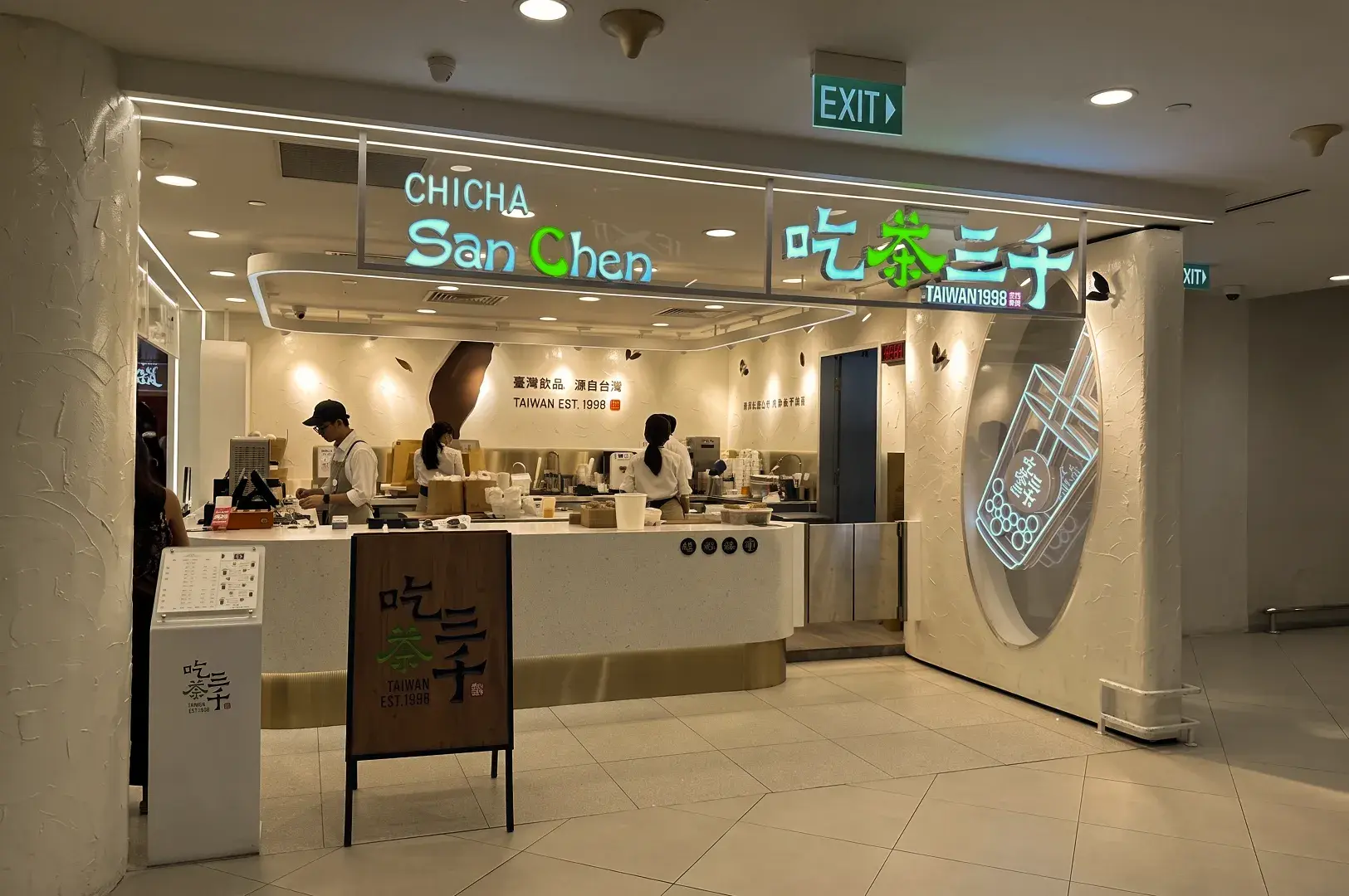 Storefront of a CHICHA San Chen tea shop featuring a clean white service counter, staff members, and illuminated signage.
