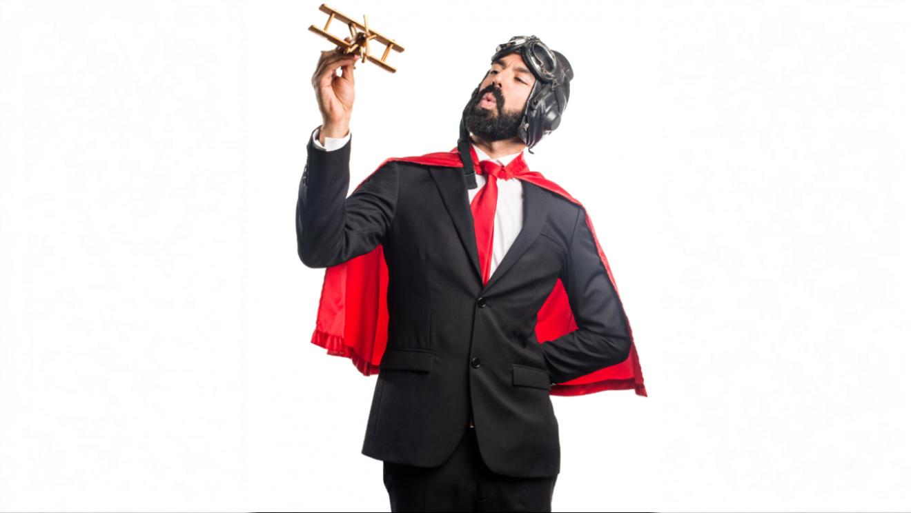 Man in a business suit and red cape holding a toy airplane, symbolizing launching a client communication platform for resellers.