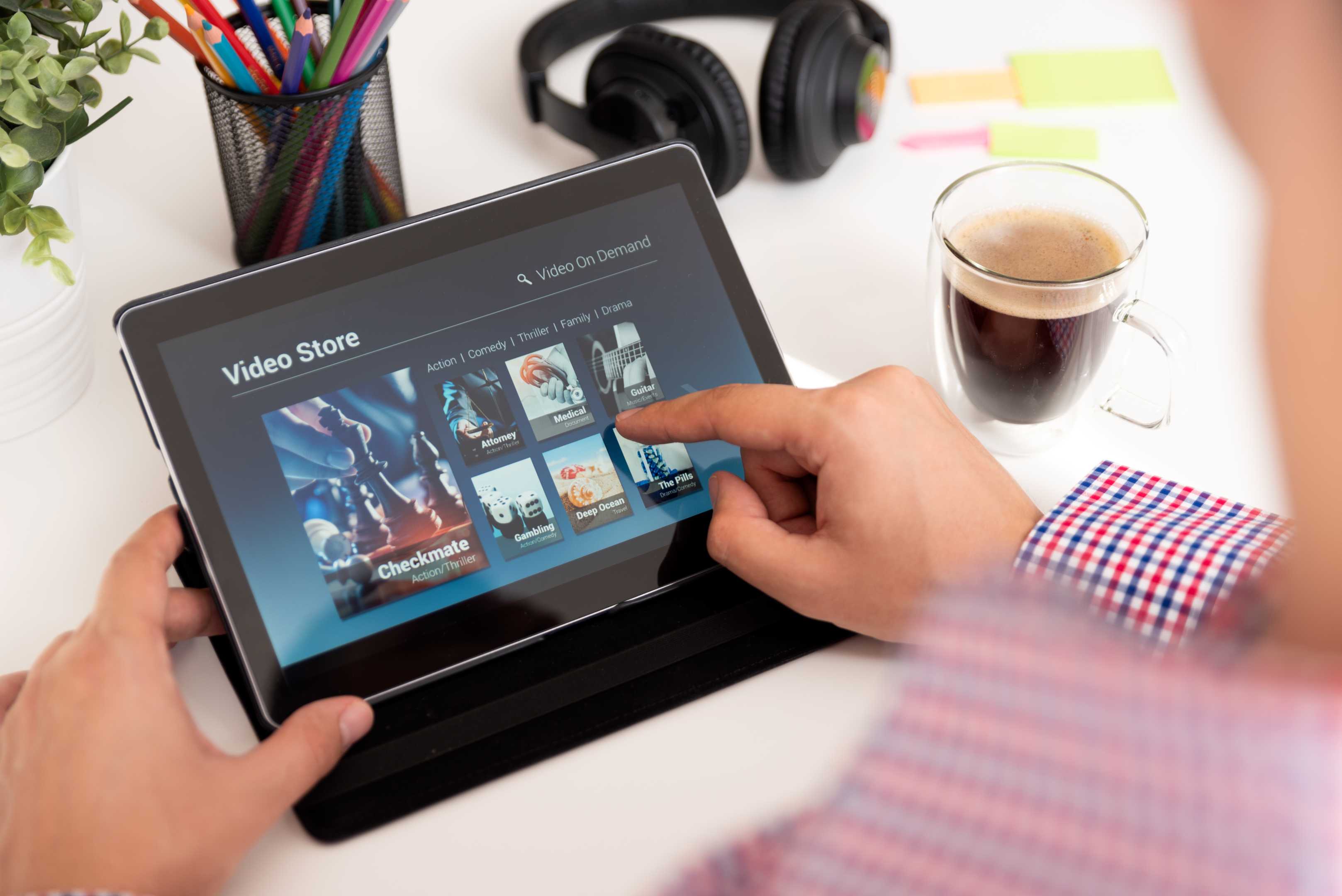 a person browses a video store on their tablet while sitting at their desk