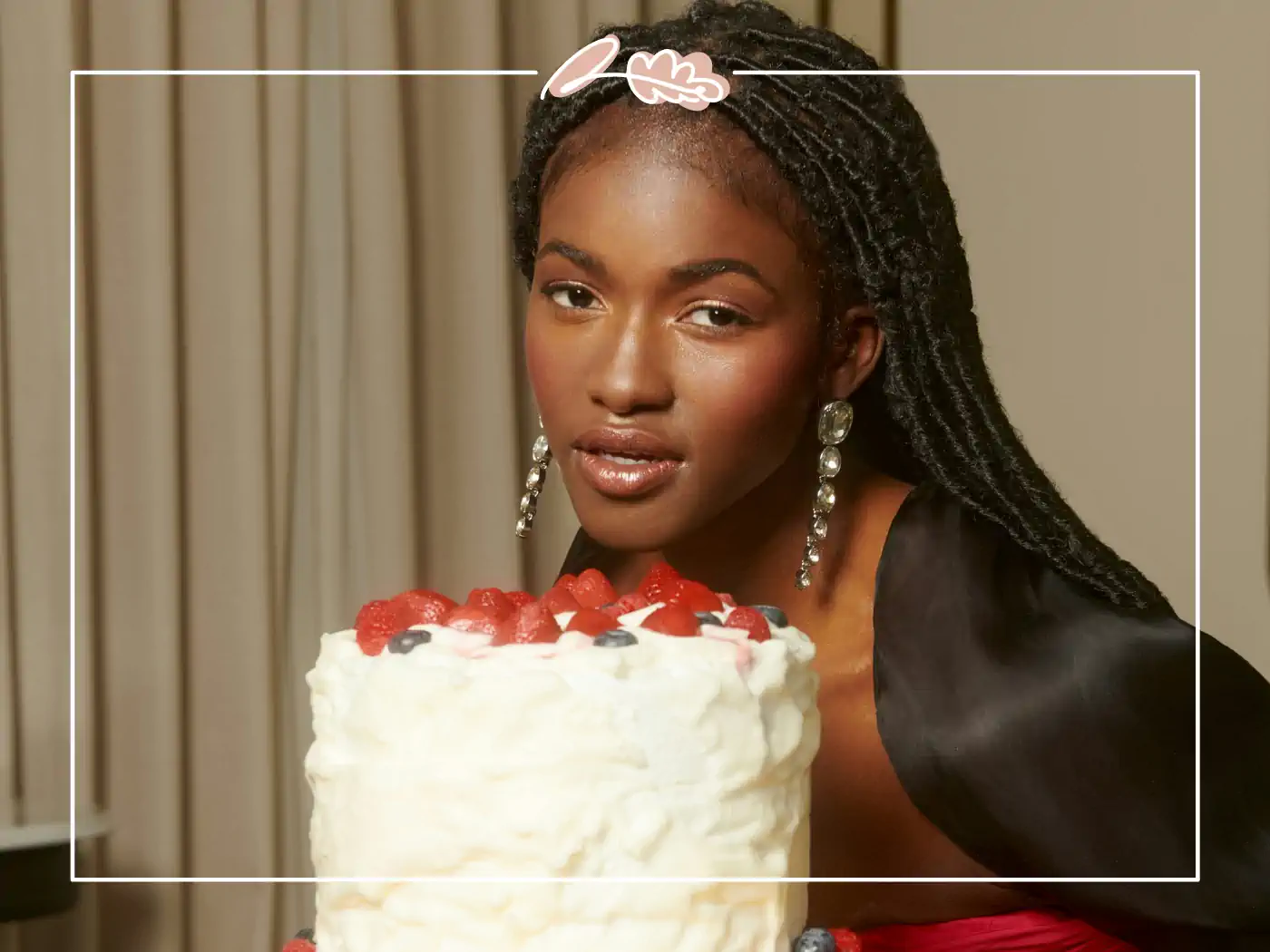 A woman holding a strawberry-topped cake smiles elegantly. Fabulous Flowers and Gifts.