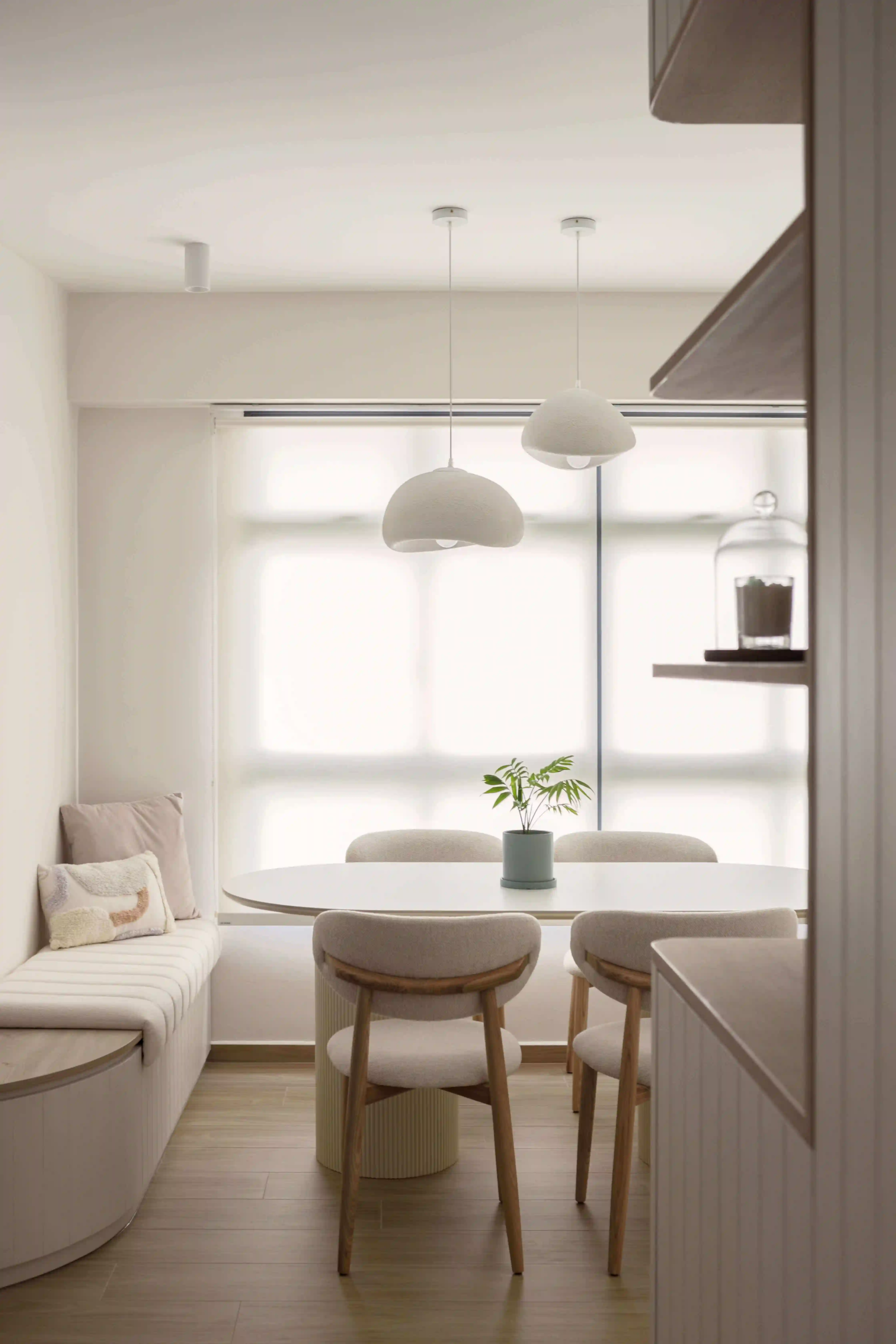 Modern Scandinavian dining corner bathed in soft daylight, highlighted by sculptural smart lights suspended above a cosy banquette
