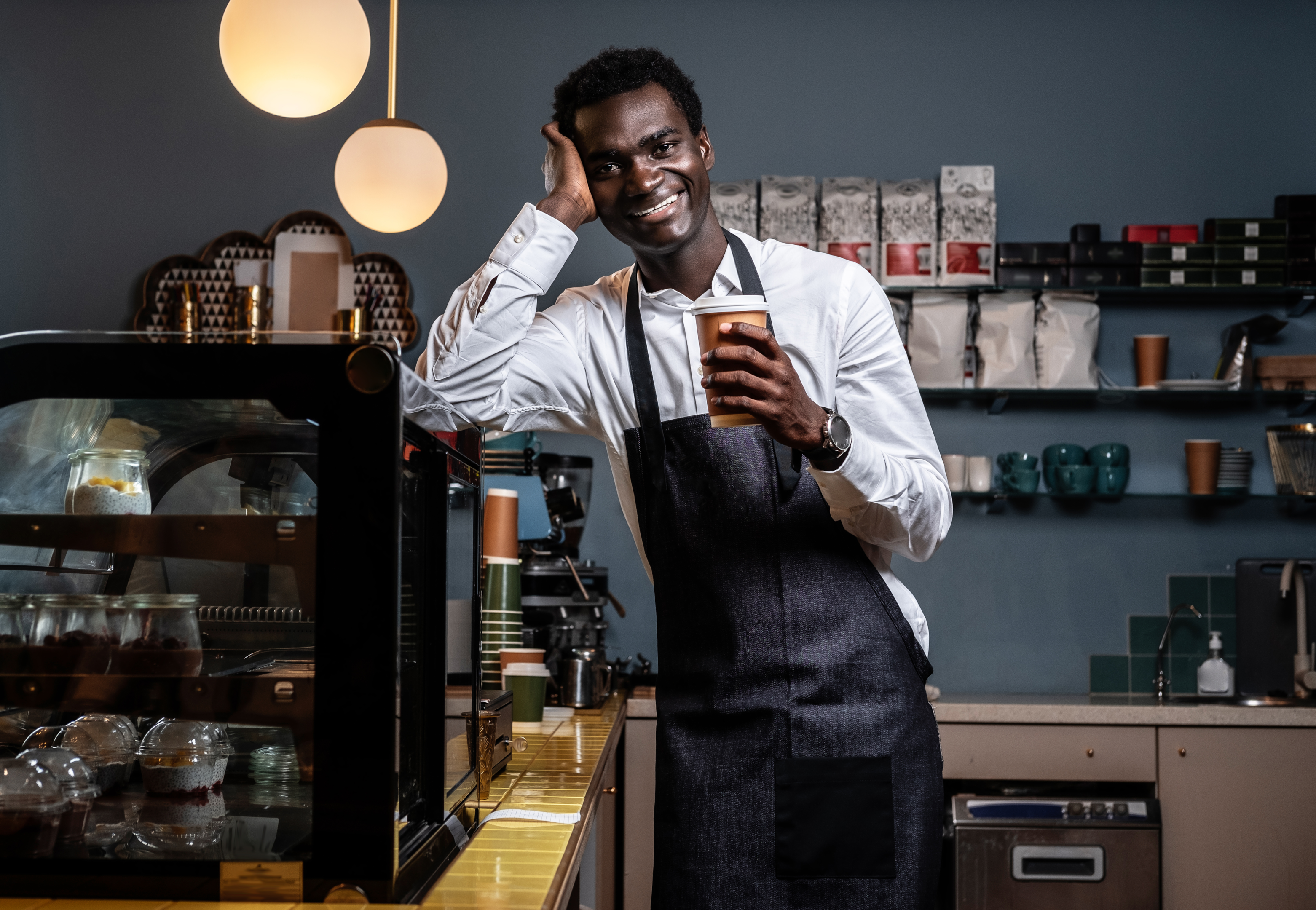 Barista sorrindo com um café. Fonte: Freepik.