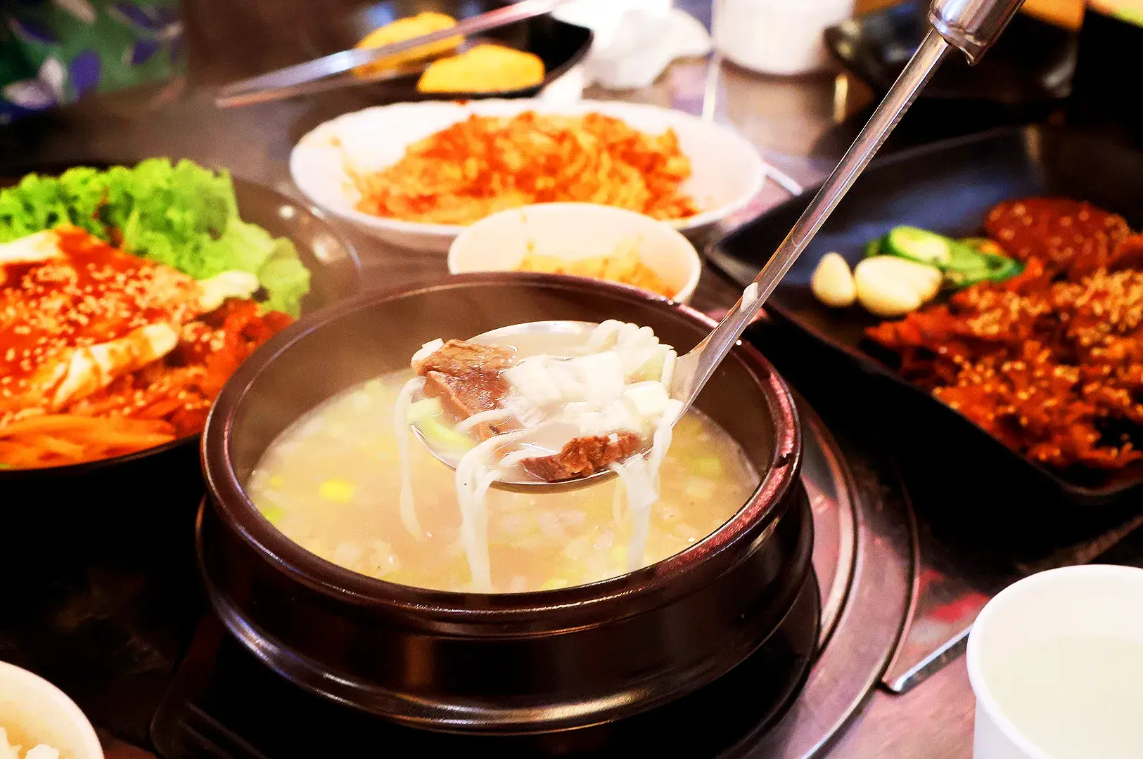 Korean soup with beef and glass noodles served with kimchi and traditional Korean side dishes