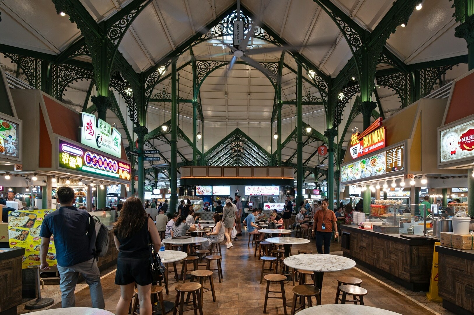 A bustling food court at a Singapore hawker centre, featuring various food stalls and diverse cuisine options.