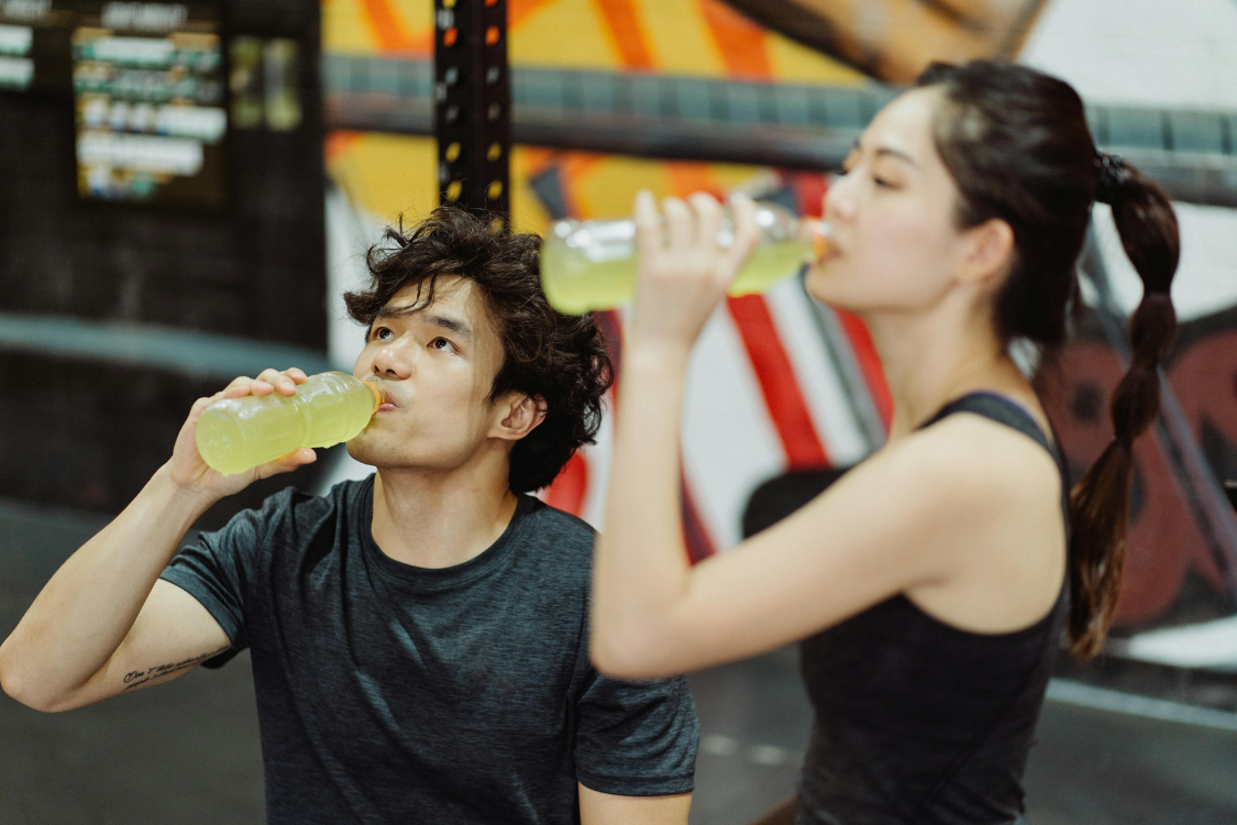 Two athletes drinking sports drinks after workout to support hydration and energy