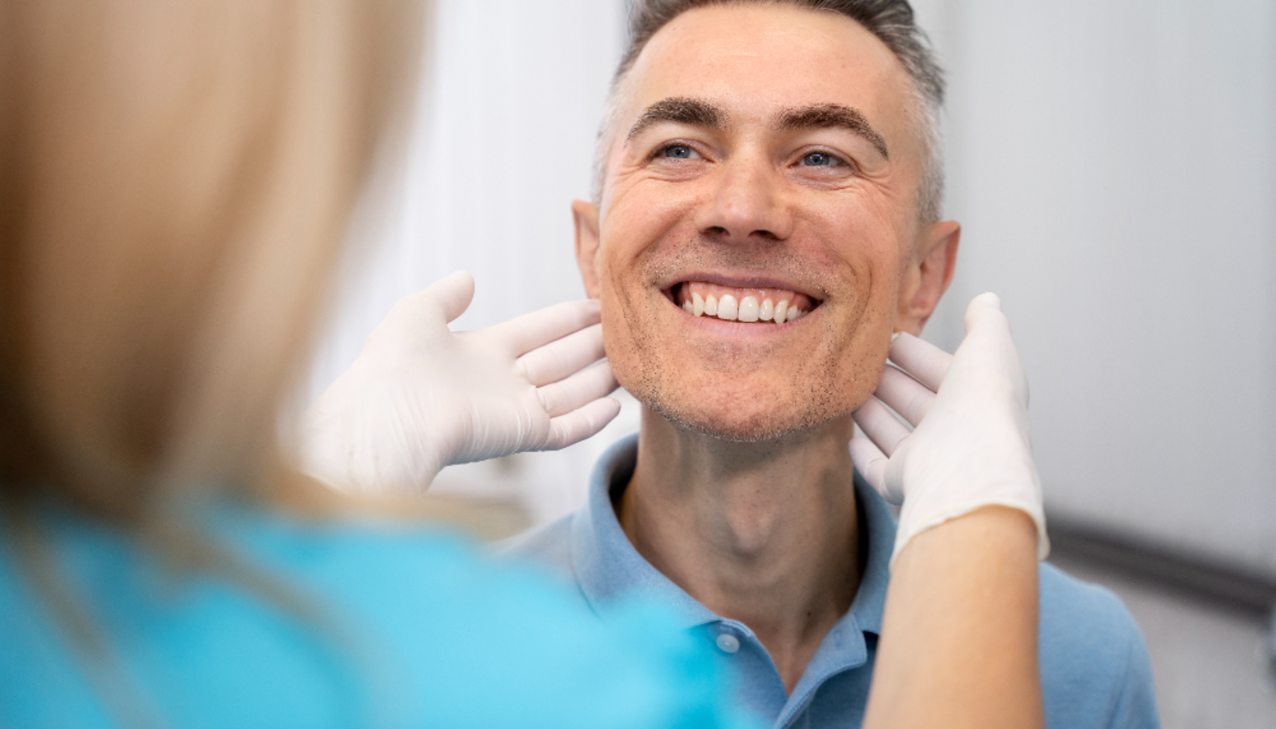 Smilende mann får undersøkt kjeven av en tannlege iført hansker under rutinekontroll.