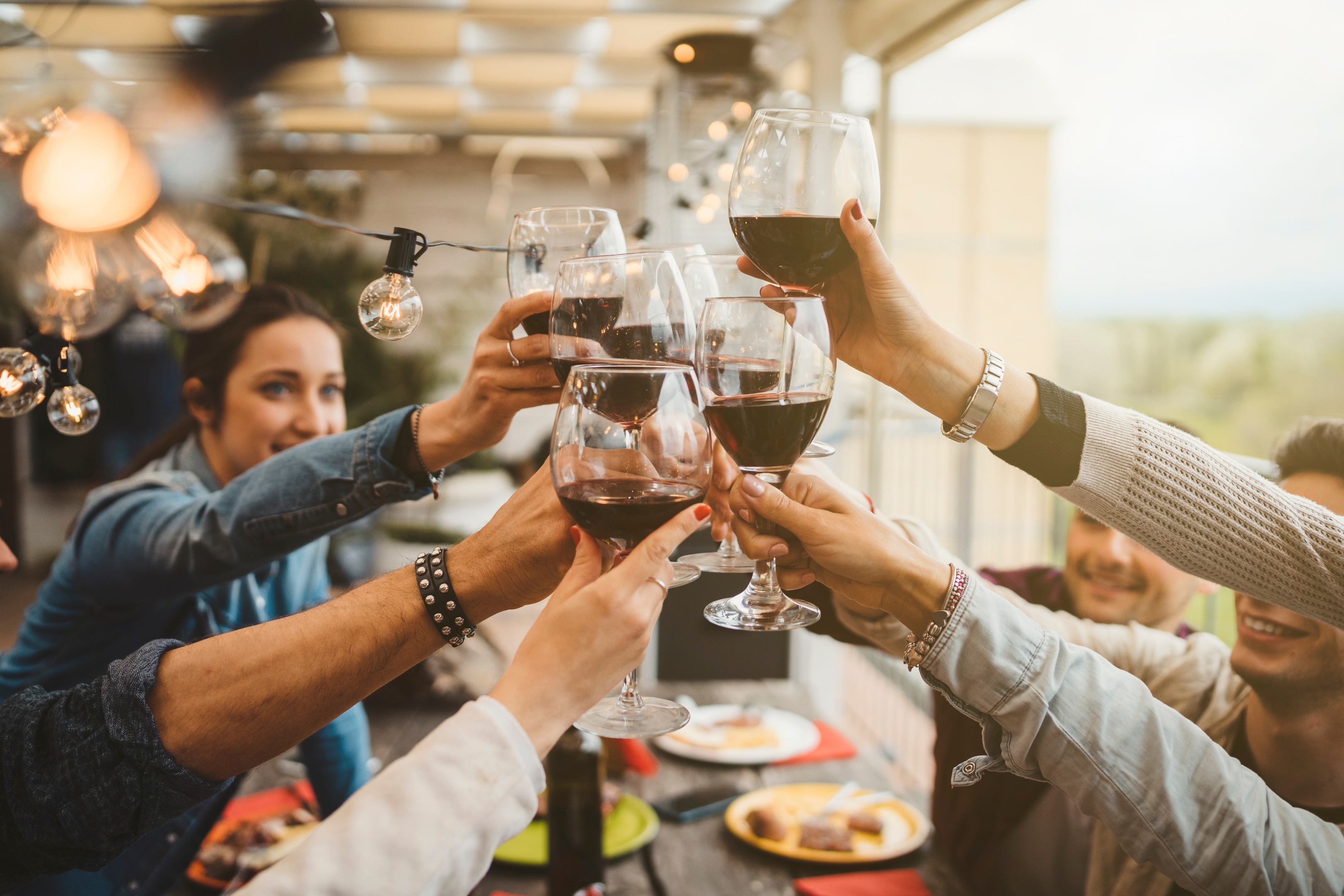 A group of friends toasting with glasses of red wine.