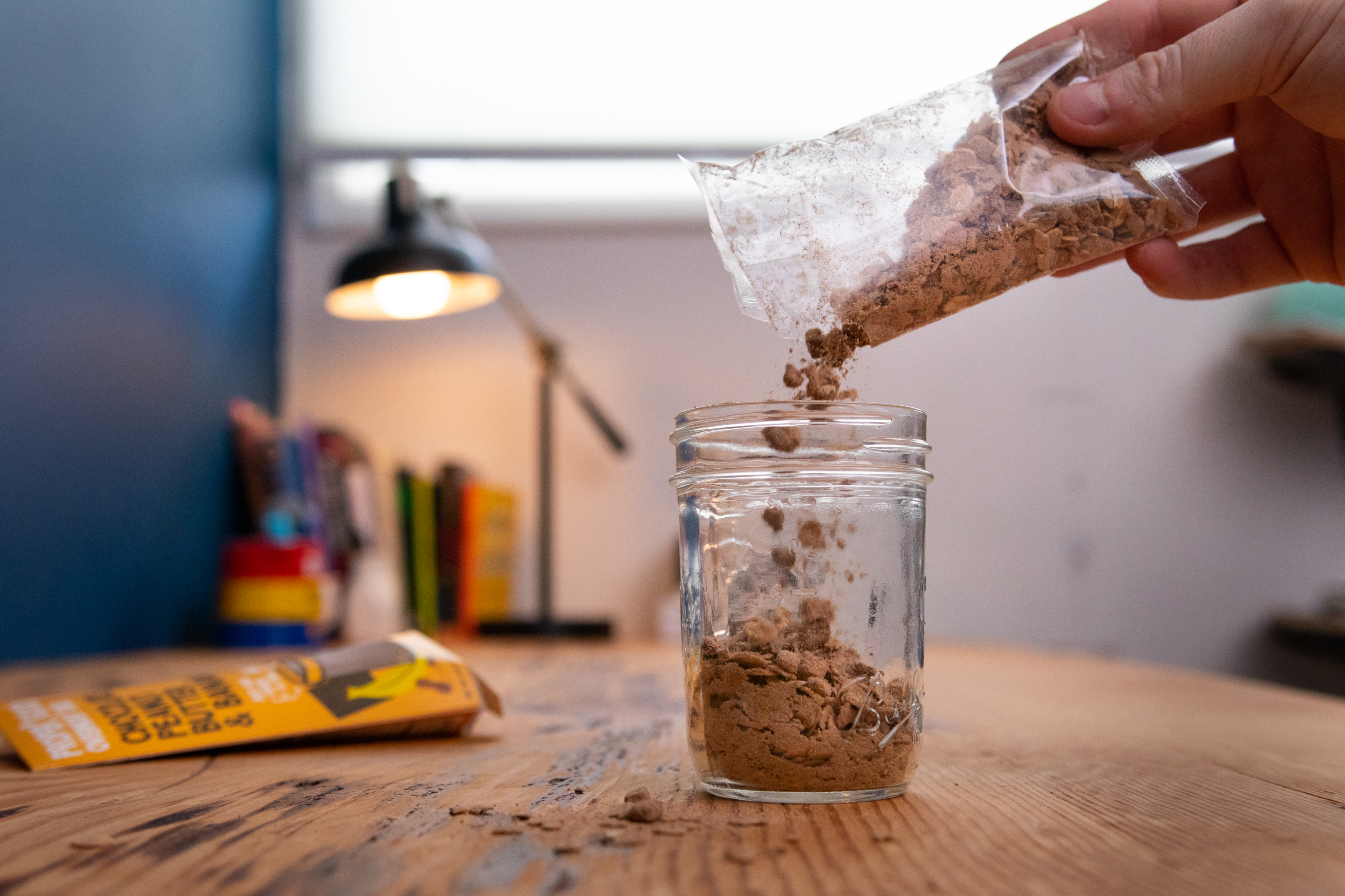 Pouring a packet of Chocolate, Peanut Butter, & Banana Overnight Oats into a Proper Good Jar