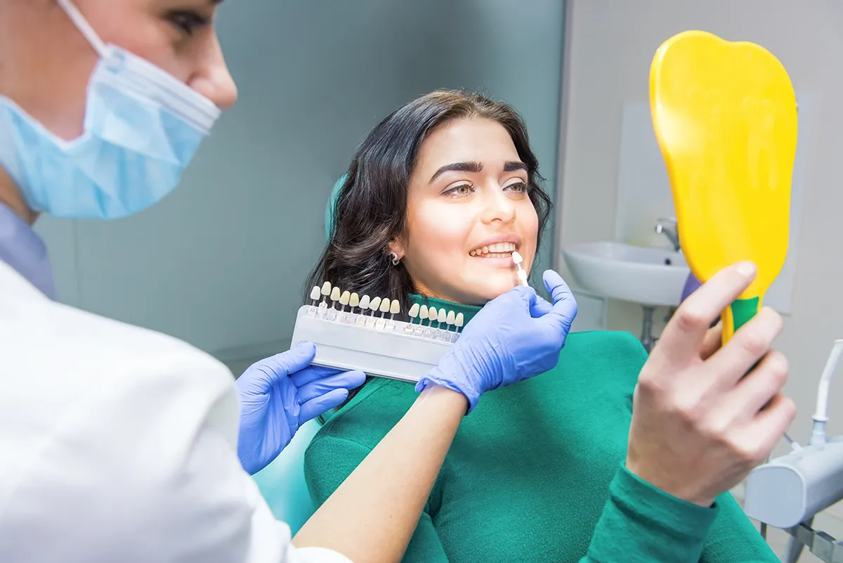 Dentist comparing patient's smile with teeth shade guide sample