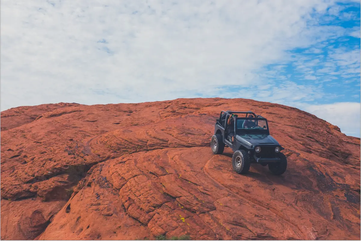 Black jeep descends red rocks while driving off-road