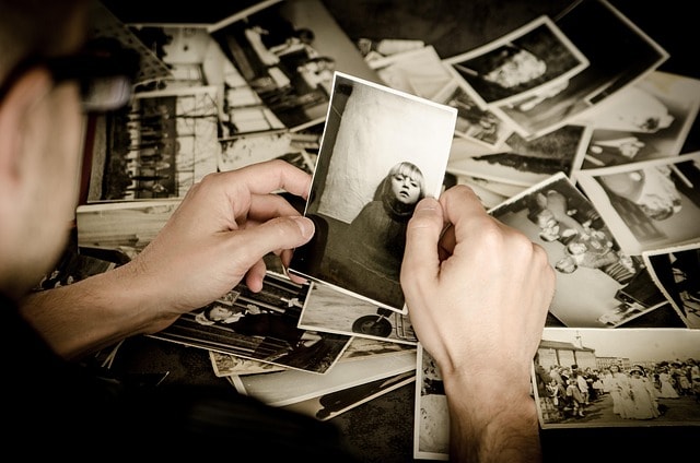 A person looking at old photographs, representing writing memories in travel writing.
