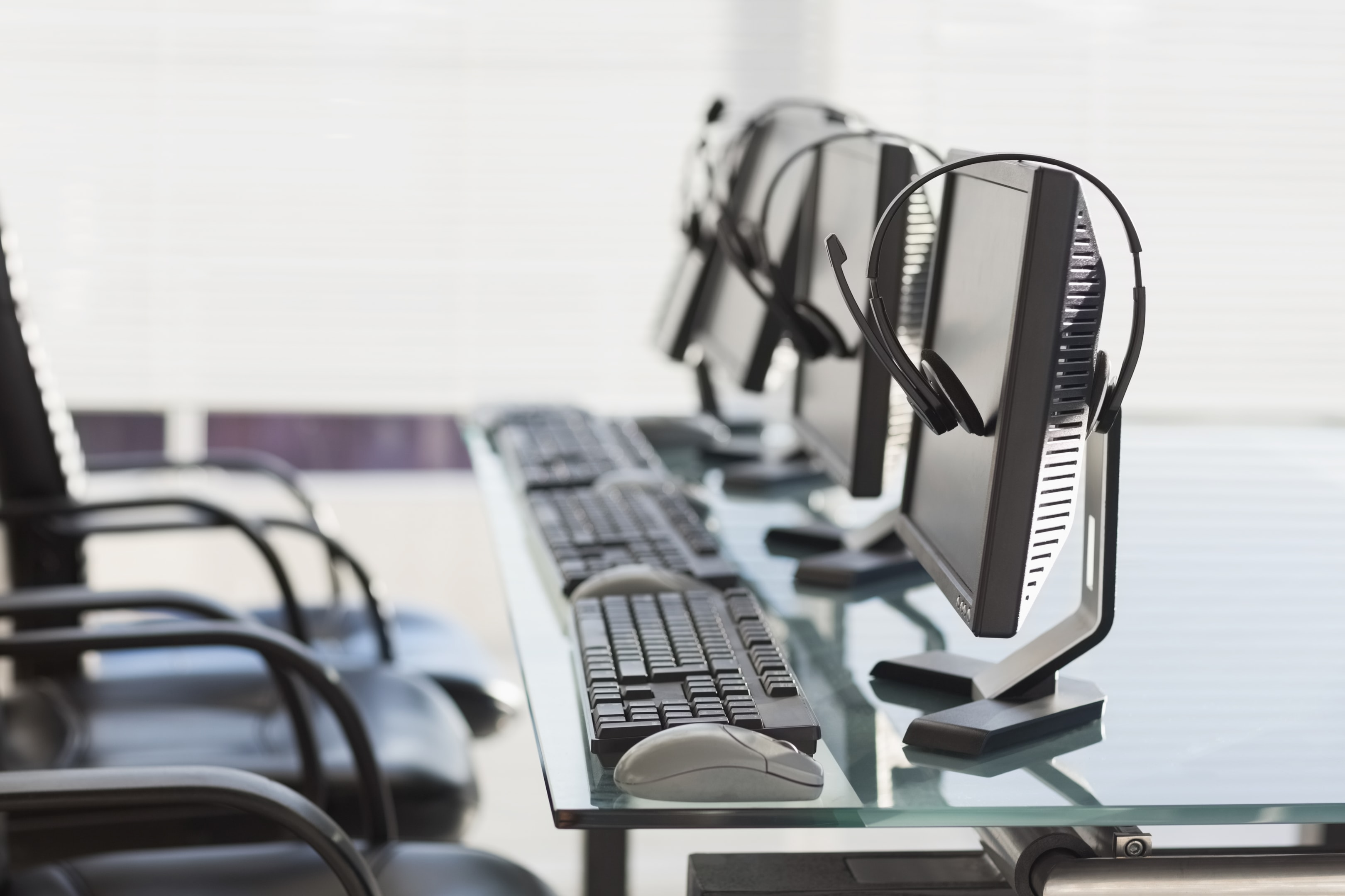 Workstations equipped with headsets and screens showcase a streamlined business phone system setup, supporting efficient office communication systems in a professional setting.