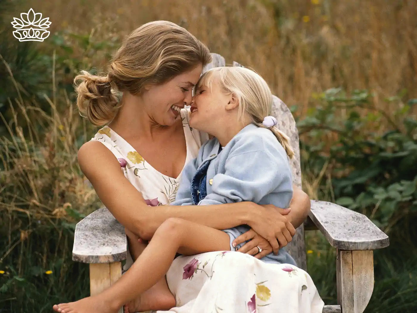 A mother and daughter sharing a loving moment outdoors. Fabulous Flowers and Gifts - Mother's Day Gift Boxes.