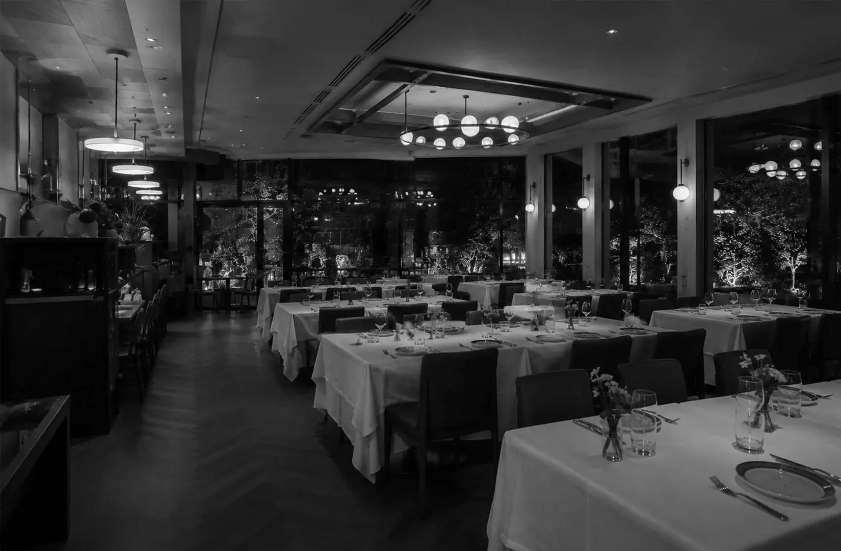 Elegant dining room at Artemis Grill & Sky Bar with floor-to-ceiling windows and a refined evening ambiance.