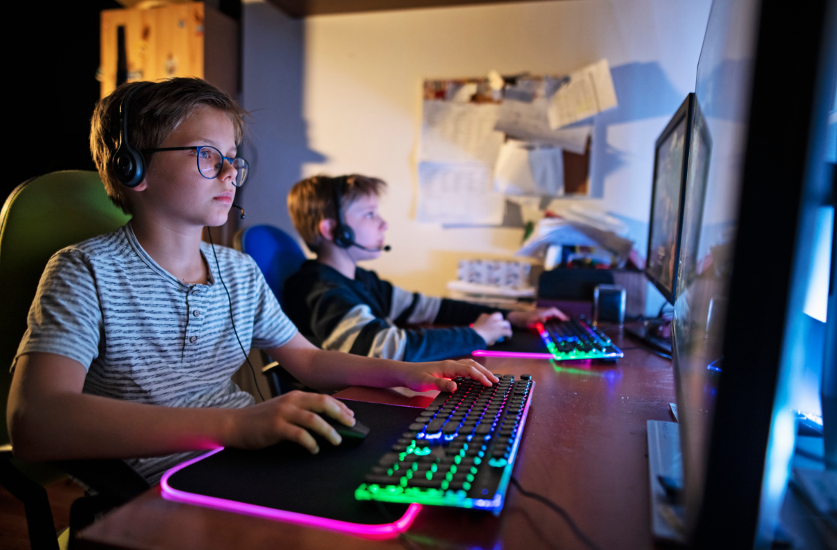 Two boys wearing headsets and playing PC games