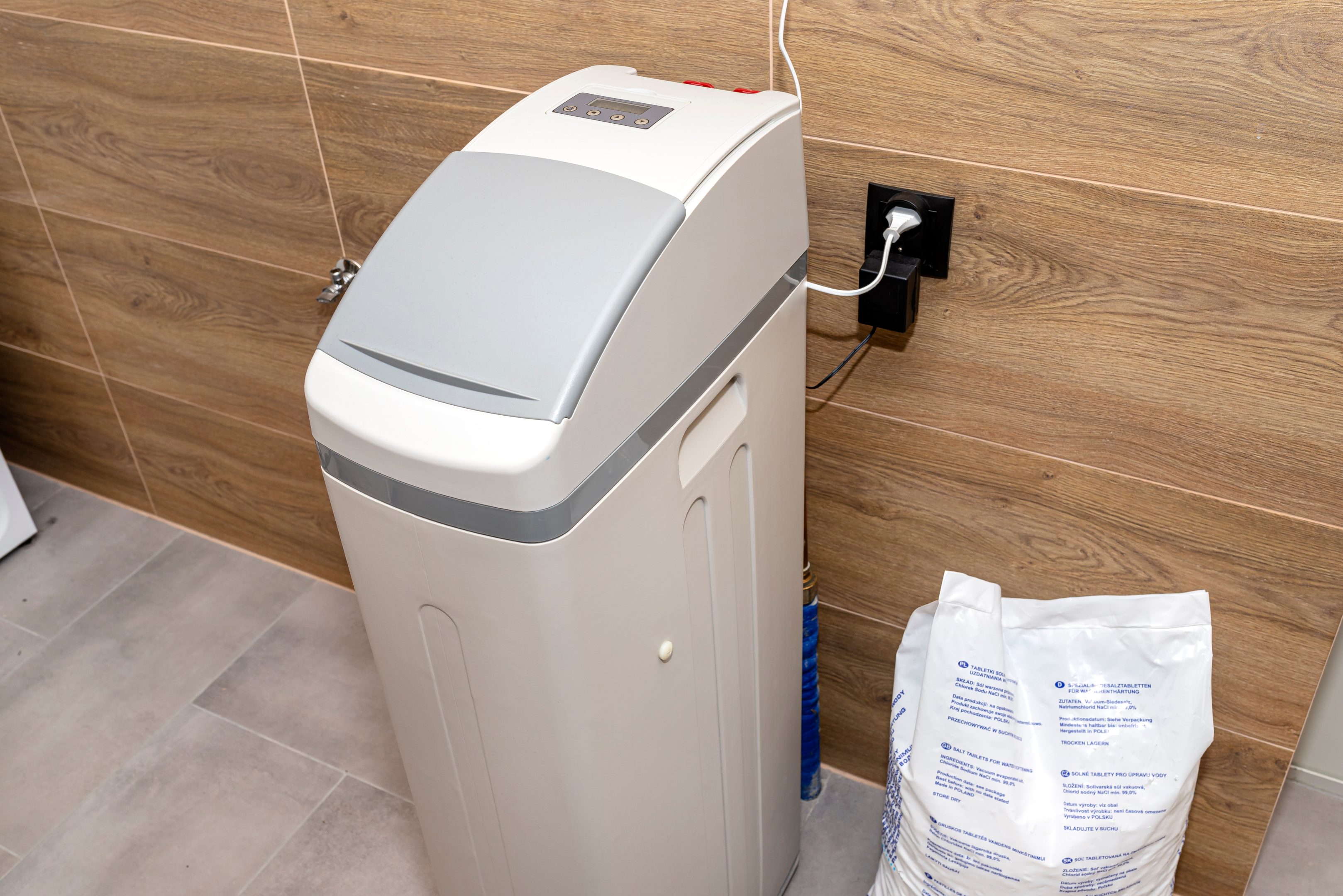 A person installing a water softener system in a home