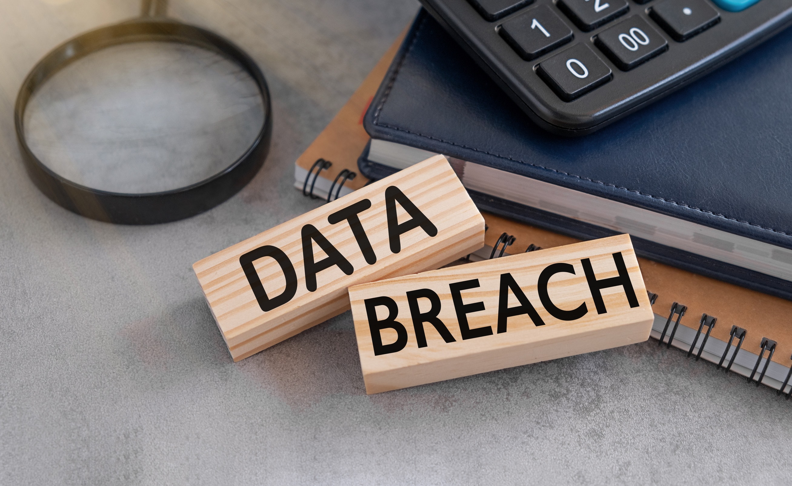Two wooden blocks reading the words data breach lay on a desk.