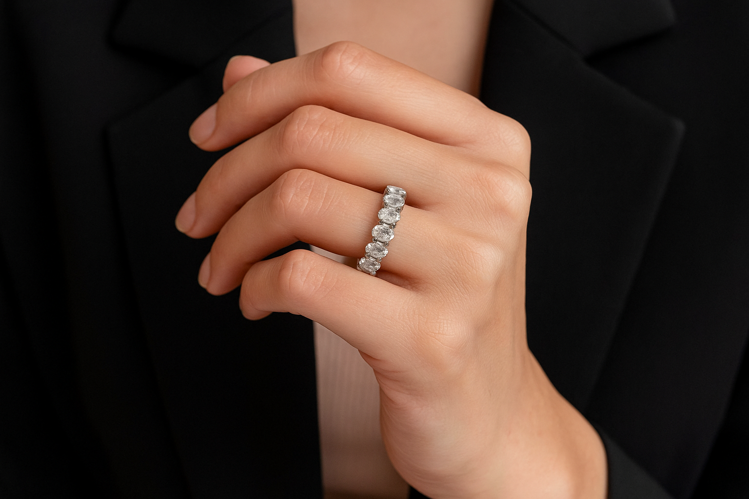 Stilingos moters ranka su baltame auksiniame žiede inkrustuota deimantine juostele su ovalo formos deimantais ratu