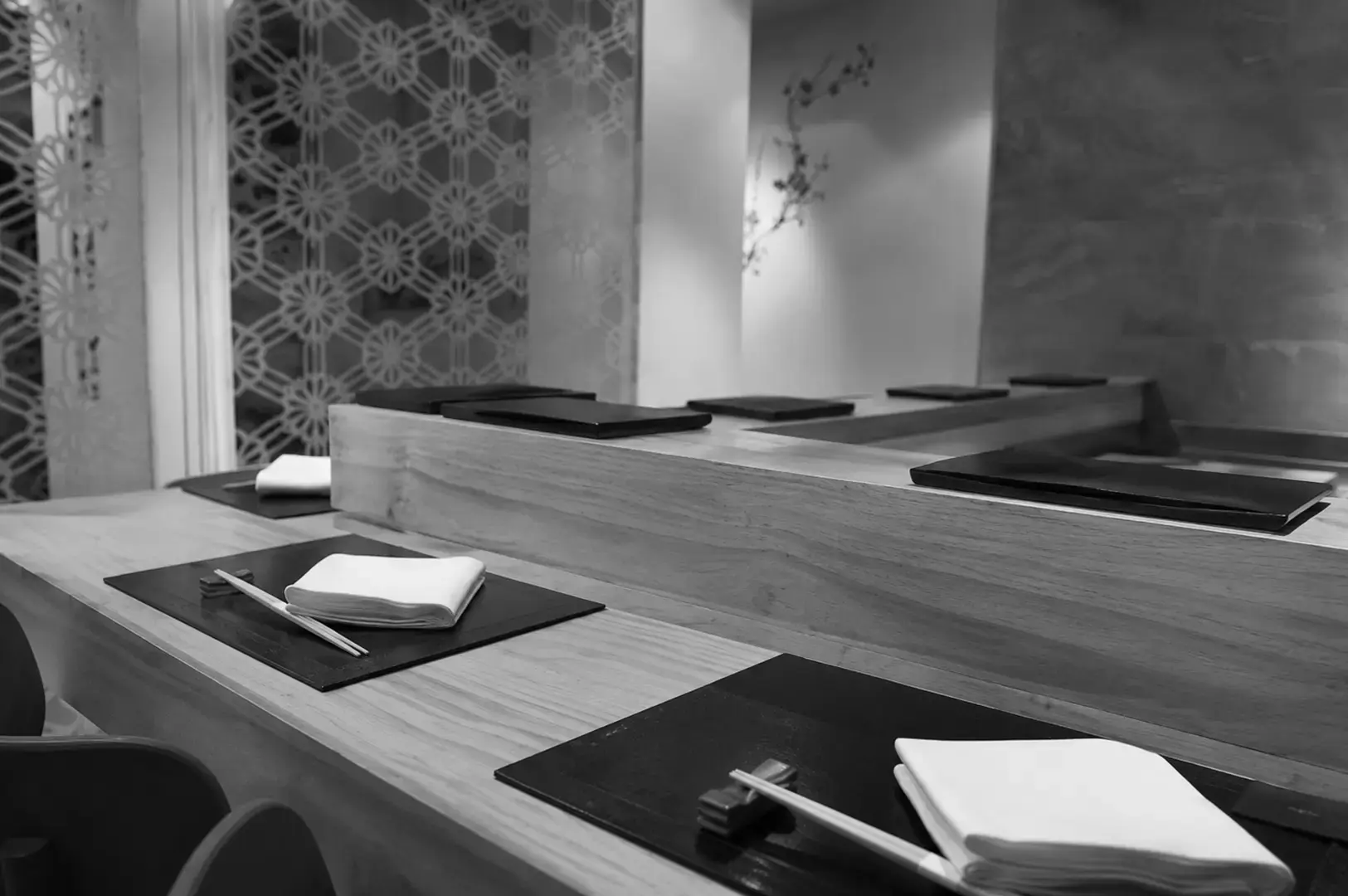 Contemporary sushi counter with wooden finishes and neatly arranged place settings.