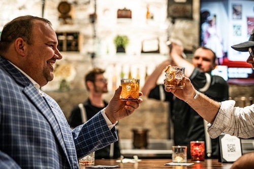 Well-dressed men enjoying craft cocktails in a hidden bar, a top pick for the best speakeasy lounge near me
