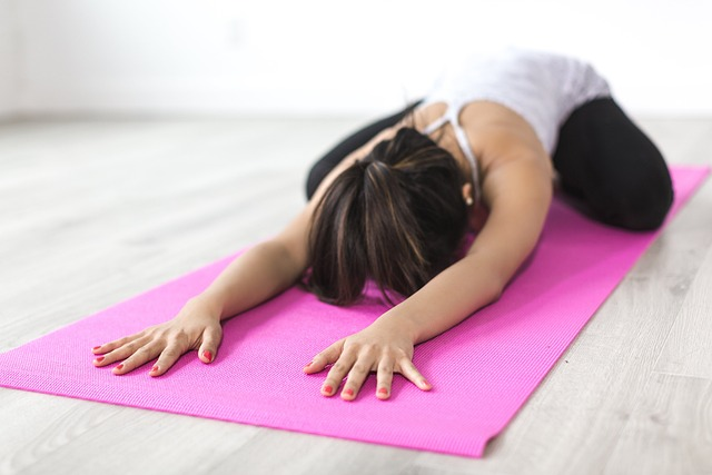 An image of a young woman face down on a yoga mat, performing the child's pose.