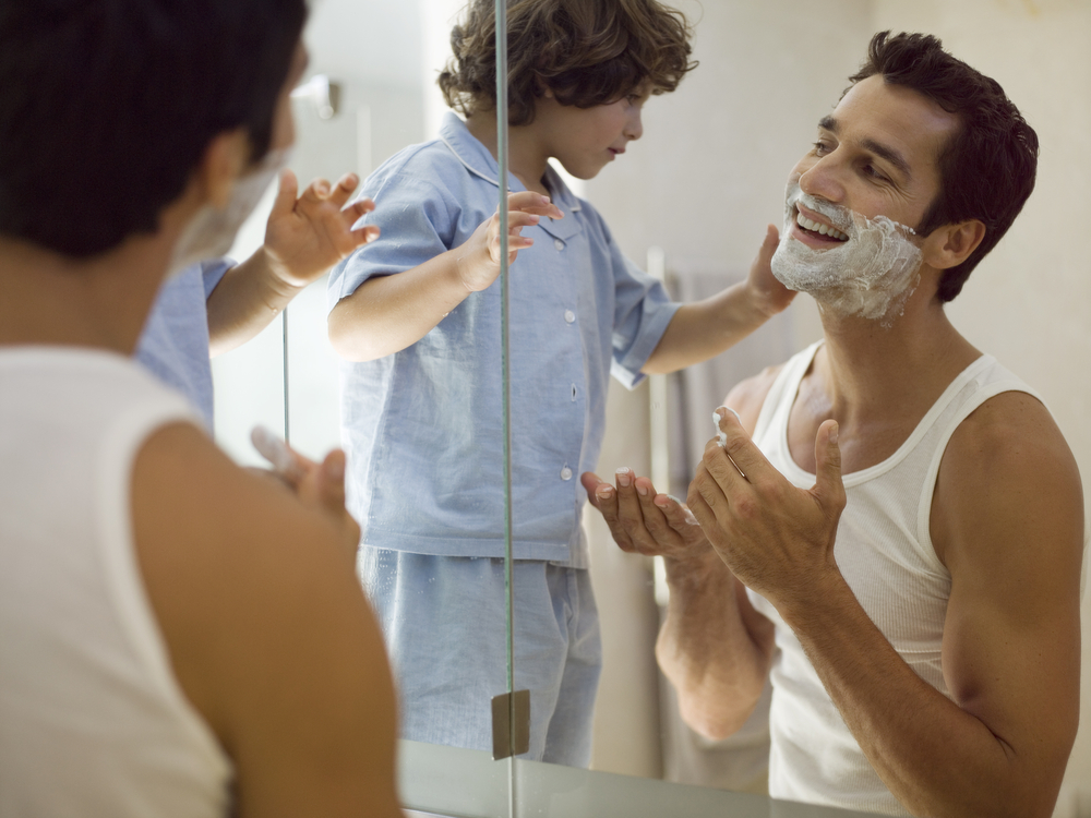 Man with shaving cream on his face playing with his young son.