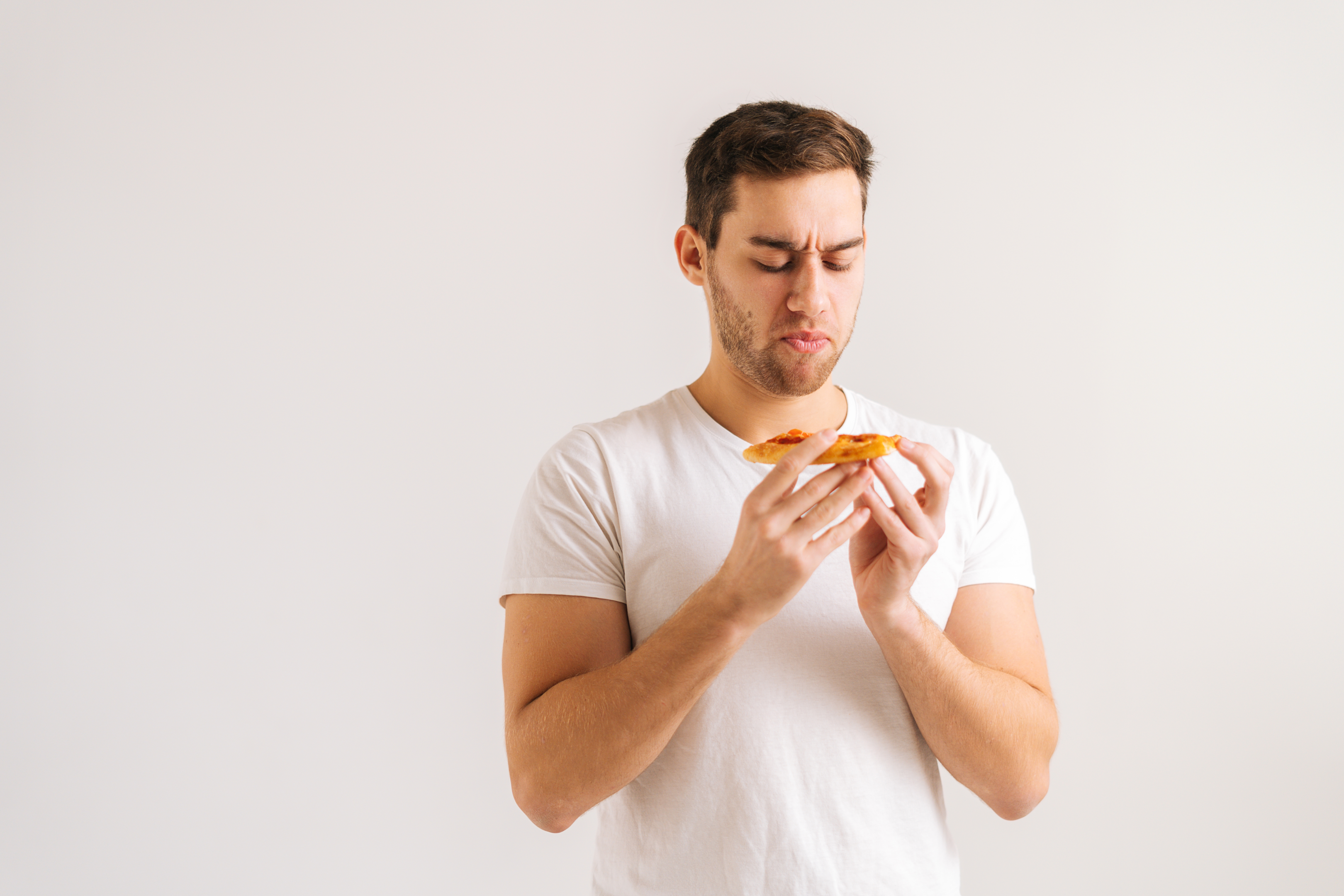 Unsatisfied hunger from man eating pizza: the difference between emotional and physical eating.