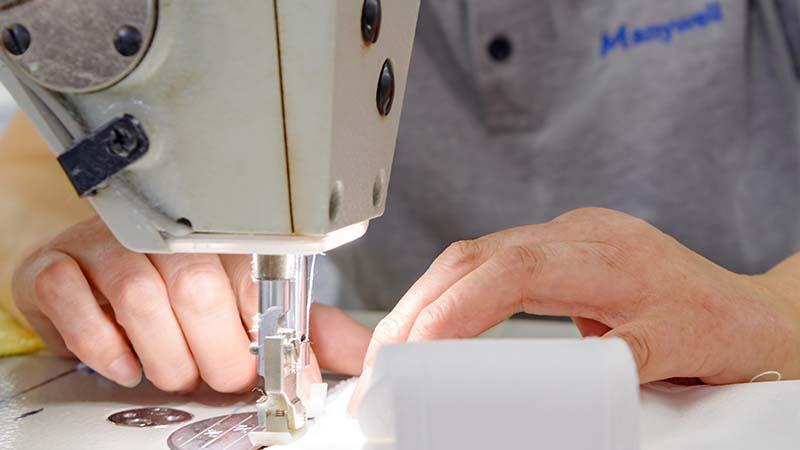 A man hand stitching the edges on a Manywell microfiber towel